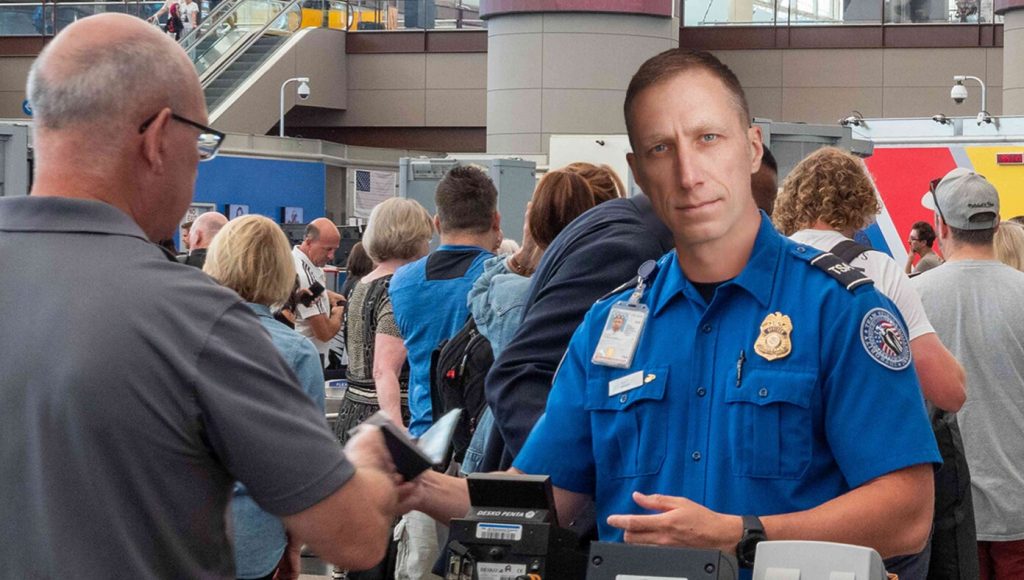 SATIRE – TSA Agent Flips Coin Every Morning To See If He’s Going To Be Pleasant Or Bellow At You Like Drill Sergeant