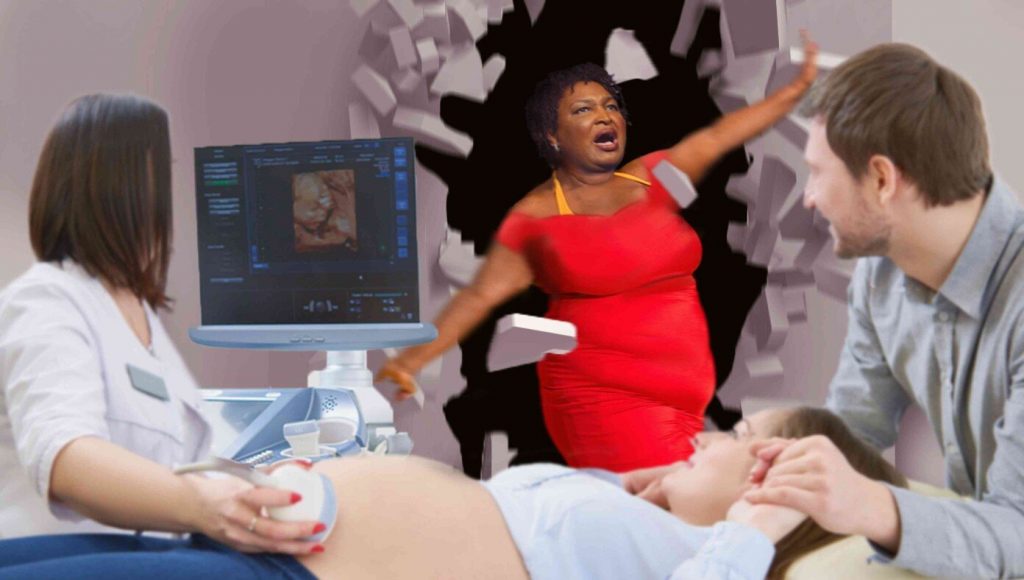 SATIRE – Stacey Abrams Bursts Through Wall Like Kool-Aid Man To Tell Overjoyed Mother That The Heartbeat Sound She’s Hearing Is Fake